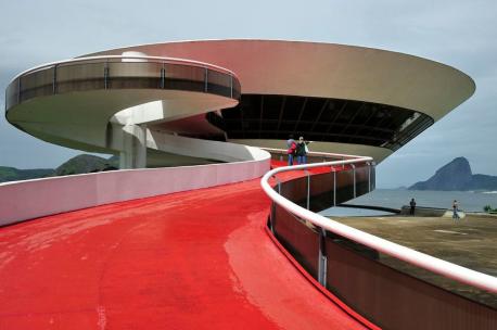 The Niteroi Contemporary Art Museum, Rio de Janeiro, Brazil - This building was designed by architect Oscar Niemeyer and completed in 1996. The UFO-shaped building overlooks the cliffs of Guanabara Bay, with sharp lines and sleek curves accenting the concrete and glass structure. Visitors can see awesome views of the bay from the exhibition floors and the auditoriums in the basement. The ramp to the entrance looks like a winding red carpet leading to the lobby of the 27,000 square-foot museum. Would you like to tour this amazing structure?