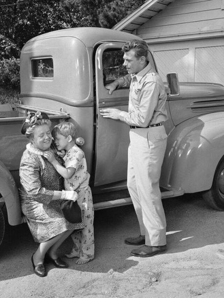 This photo is from the first episode of The Andy Griffith Show (1960-1968). Rose, Andy and Opie's housekeeper is getting married and will be moving out. Opie (played by a very young Ron Howard) is totally against her leaving. In the meantime, Andy asks his Aunt Bee to come and live with them and help take care of Opie. Opie is against this idea as well. So, Bee decides to leave. Andy is getting ready to take her to the bus station when Opie comes running out ... crying and saying: Pa, she can't go .. she doesn't know how to do anything. She can't play ball or fish. Who will take care of her? She stayed. Have you ever watched the Andy Griffith Show when it was originally aired or now in syndication? (The photo is cropped, open it in a new tab to see the full image)