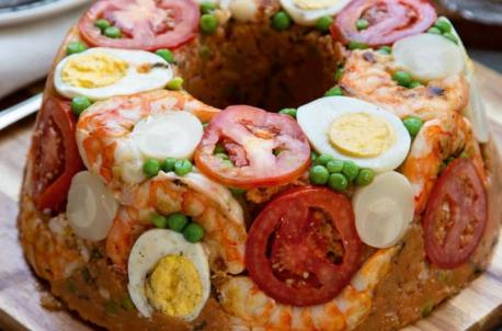 Cuscuz Paulista. This cold cake is made from corn flakes or cornmeal, tomato sauce, tomato pieces, boiled egg, and canned ingredients such as peas, green corn, olives, and sardines. This is a traditional Christmas dish from São Paulo in Brazil. Is this a dish you would be happy to have on your dinner table?