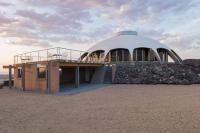 The property includes 60 acres of isolated desert near San Bernardino, California. The two-bedroom, two-bathroom, 2,206-square-foot house has an open floor plan with curved ceilings more than 9 feet high. You get complete desert views from all the main rooms, including the living room. The property also includes a separate two-story structure that contains an oversize garage and an upstairs apartment. Would you like to see the view from this house?