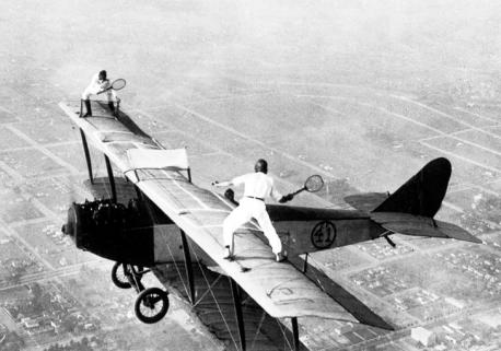 Stuntmen pretend to be playing tennis on an airplane in 1923. Would you like to be a stuntman?