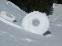 Nature has its own way of rolling snowballs 'snow donuts' which are only formed under perfect temperature conditions. Chunks of snow are blown by the wind picking up material along the way but the center tends to collapse which creates the donut shape. If you have snow where you live have you ever seen one.?